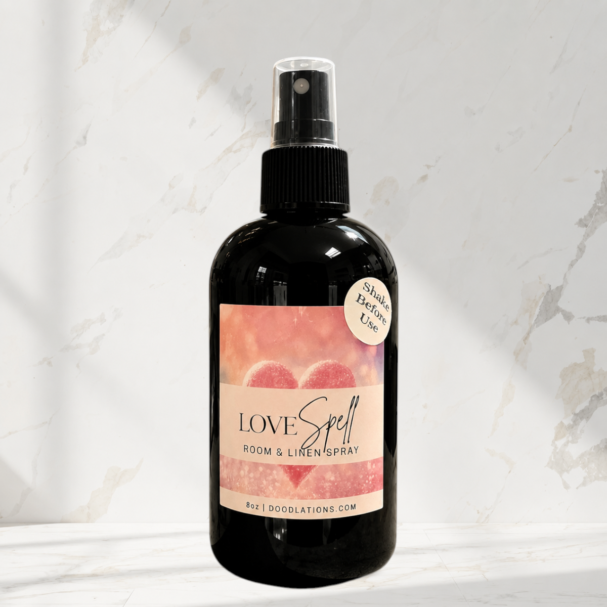 Doodlations Coffee Bar & Boutique Love Spell room and linen spray in a black bottle with a heart-themed label