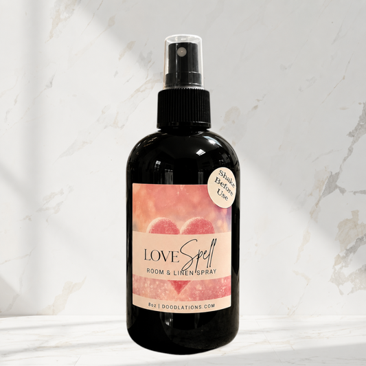 Doodlations Coffee Bar & Boutique Love Spell room and linen spray in a black bottle with a heart-themed label