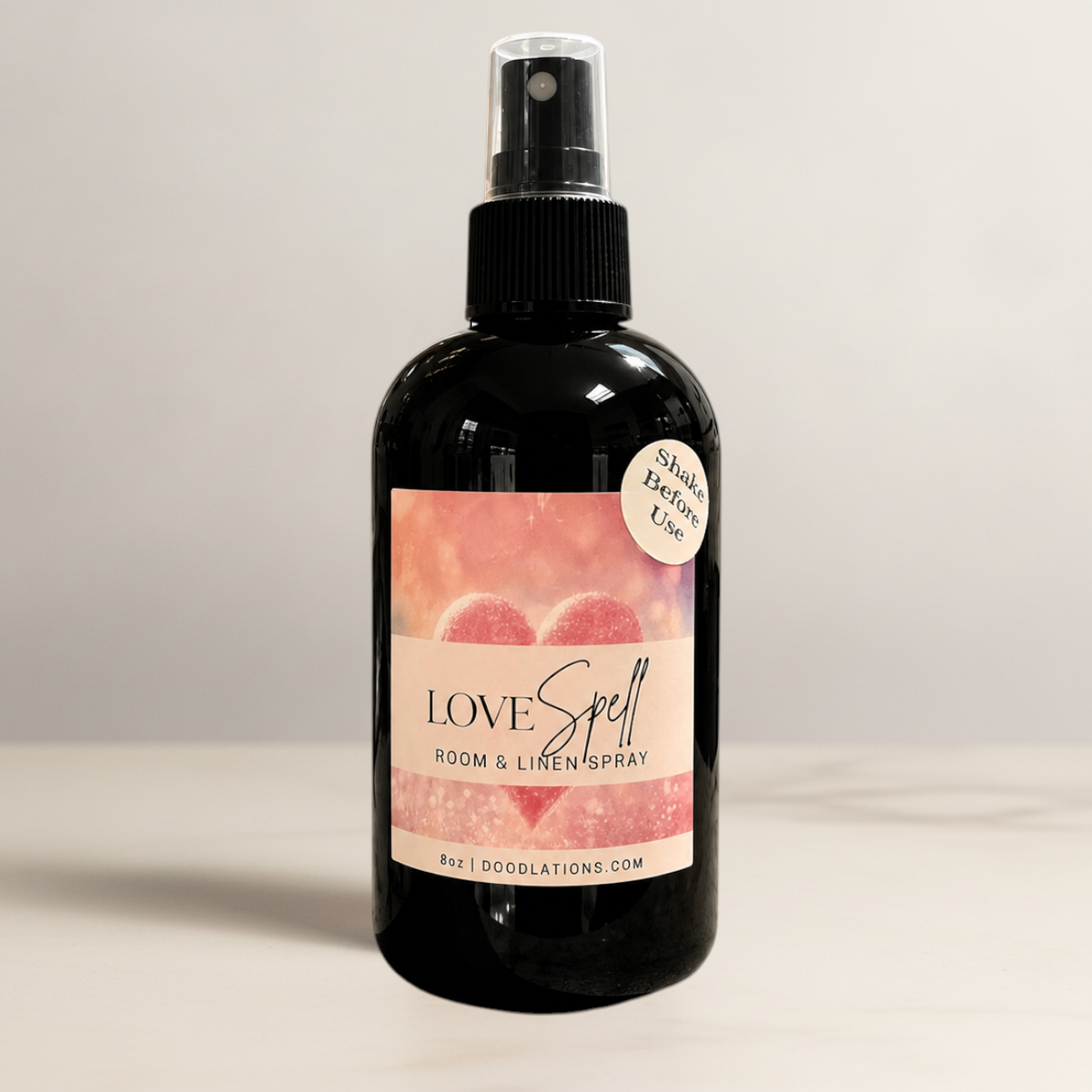 Doodlations Coffee Bar & Boutique Love Spell room and linen spray in a black bottle with a heart-themed label.