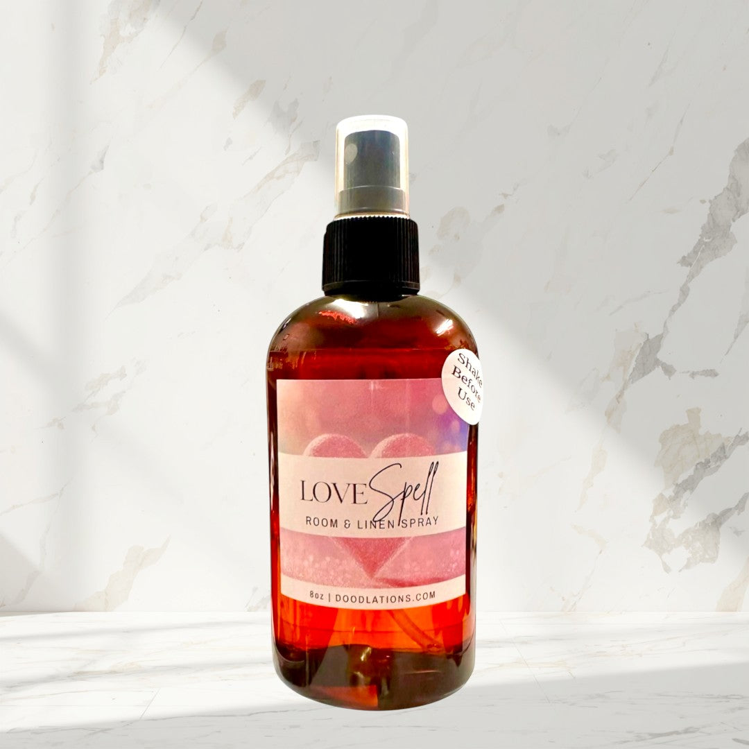 Doodlations Coffee Bar & Boutique Love Spell room and linen spray in amber bottle with pink label and hearts.