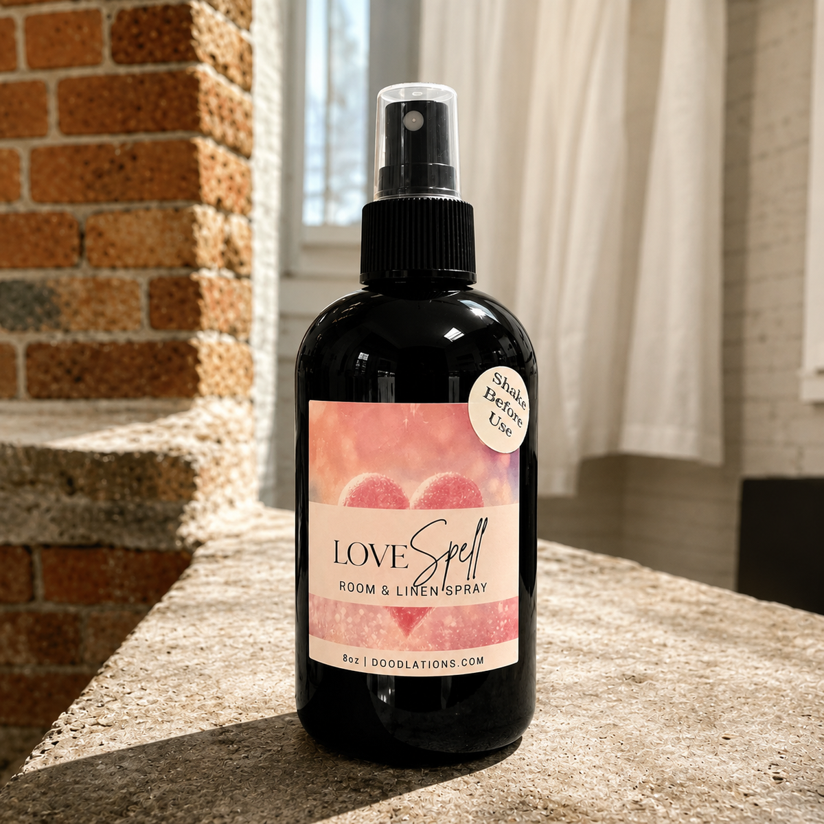 Doodlations Coffee Bar & Boutique Love Spell room and linen spray in a black bottle with a pink heart label.