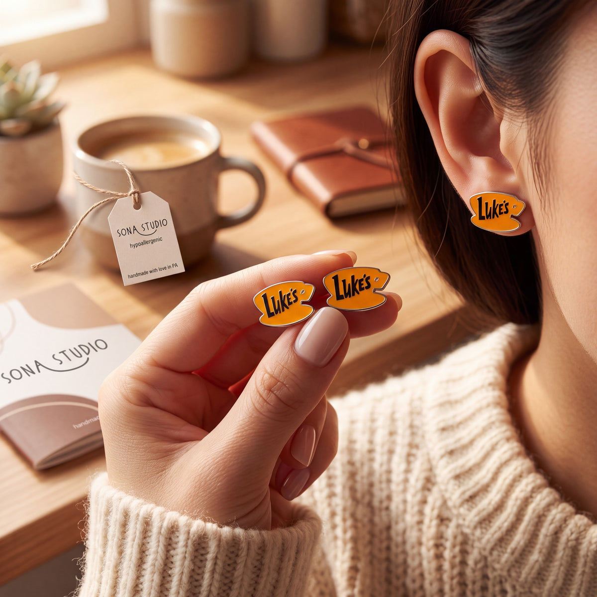 Doodlations Coffee Bar & Boutique Luke's Diner earrings featuring a yellow coffee cup design on a person's ear.