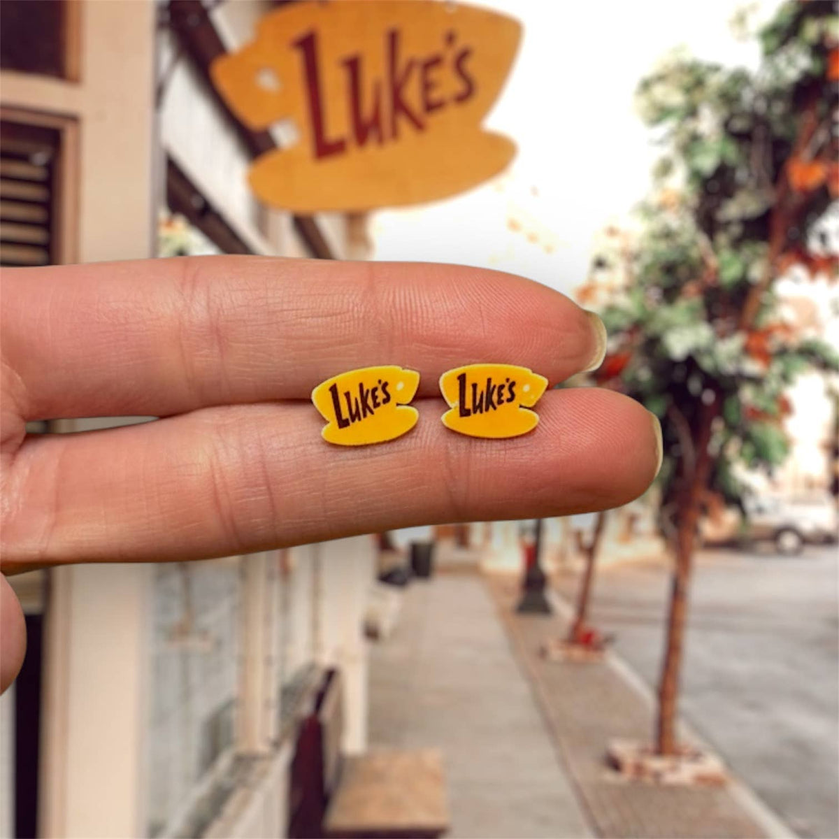 Doodlations Coffee Bar & Boutique yellow Luke's Diner stud earrings with black lettering on a hand