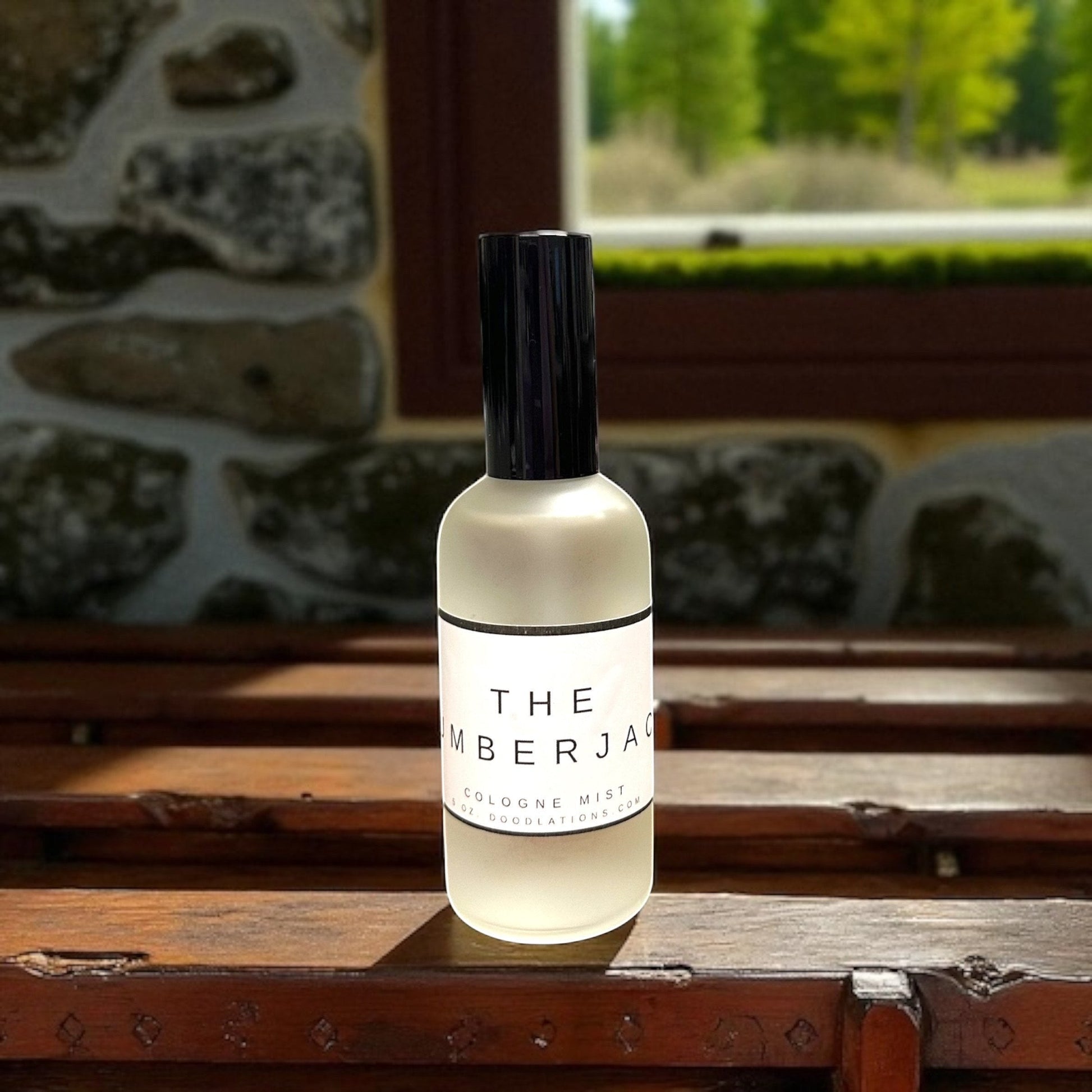 Doodlations Coffee Bar & Boutique The Lumberjack fine mist cologne in a frosted glass bottle on a wooden bench