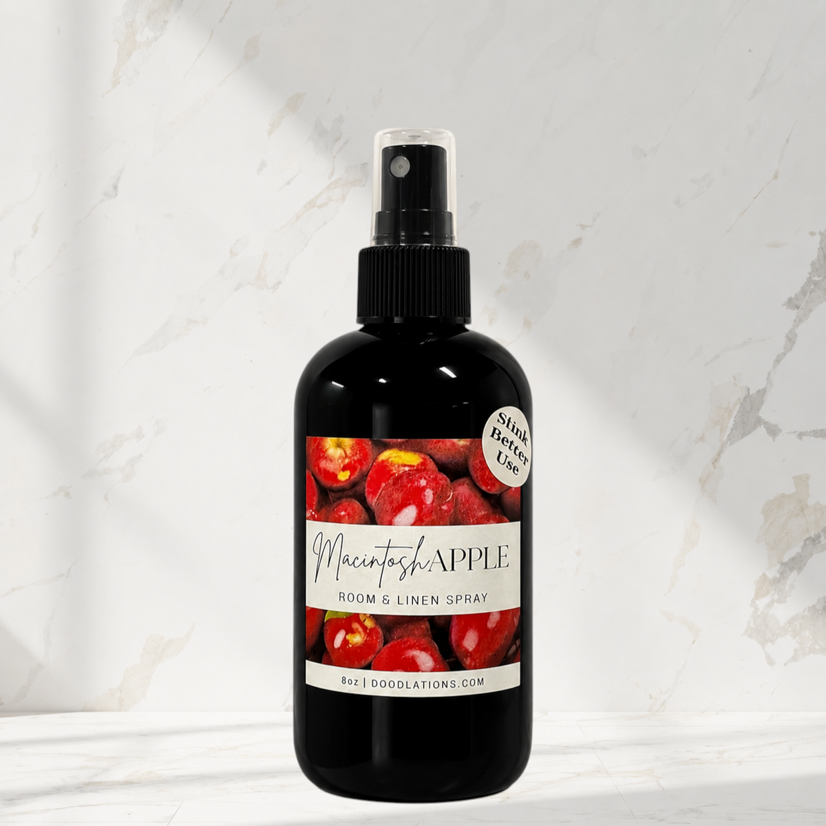 Doodlations Coffee Bar & Boutique Macintosh Apple room and linen spray in a black bottle against a marble background