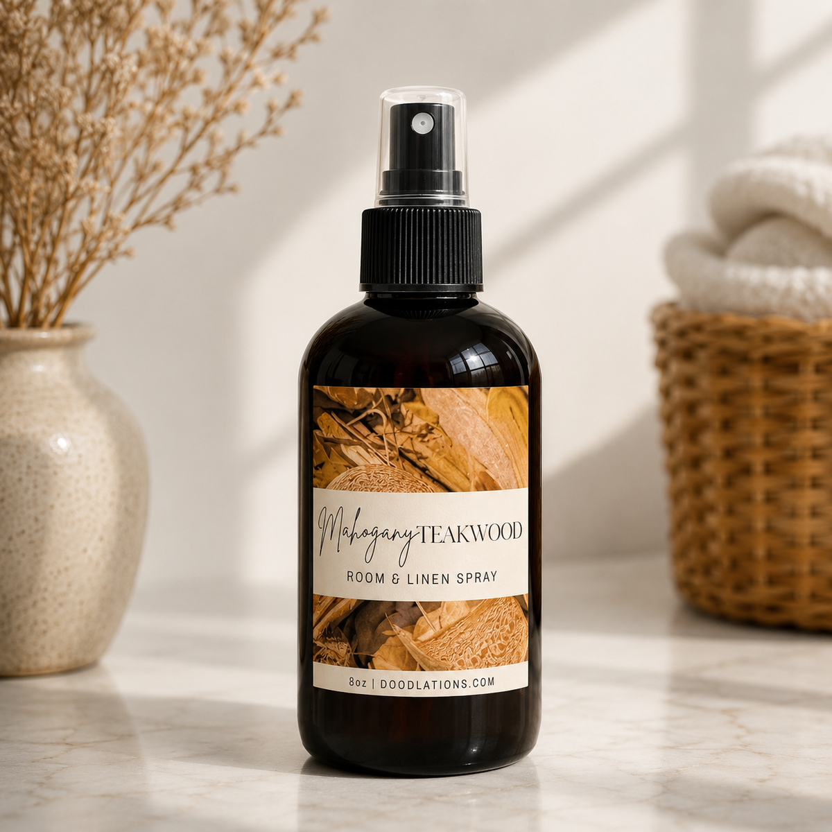 Doodlations Coffee Bar & Boutique Mahogany Teakwood room and linen spray in an amber glass bottle on a marble surface.
