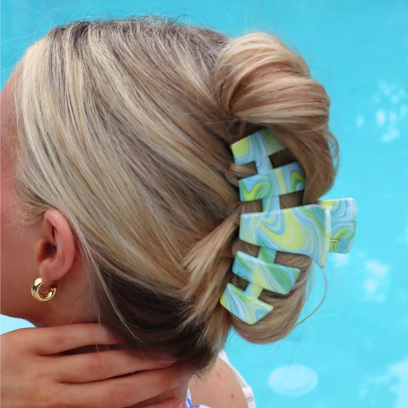 Doodlations Coffee Bar & Boutique hair claw clip with a blue and lime green marble pattern holding a blonde bun