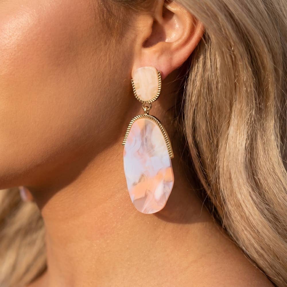 Doodlations Coffee Bar & Boutique marble teardrop earrings with gold-tone metal accents worn on a woman's ear.