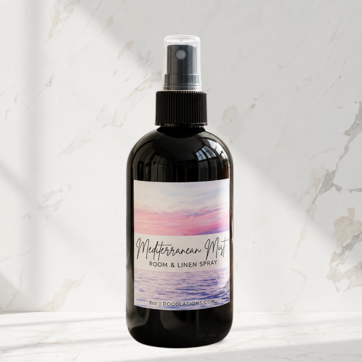 Doodlations Coffee Bar & Boutique Mediterranean Mist room and linen spray in a black bottle on a marble surface.