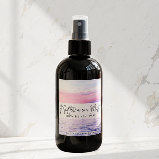 Doodlations Coffee Bar & Boutique Mediterranean Mist room and linen spray in a black bottle on a marble surface.