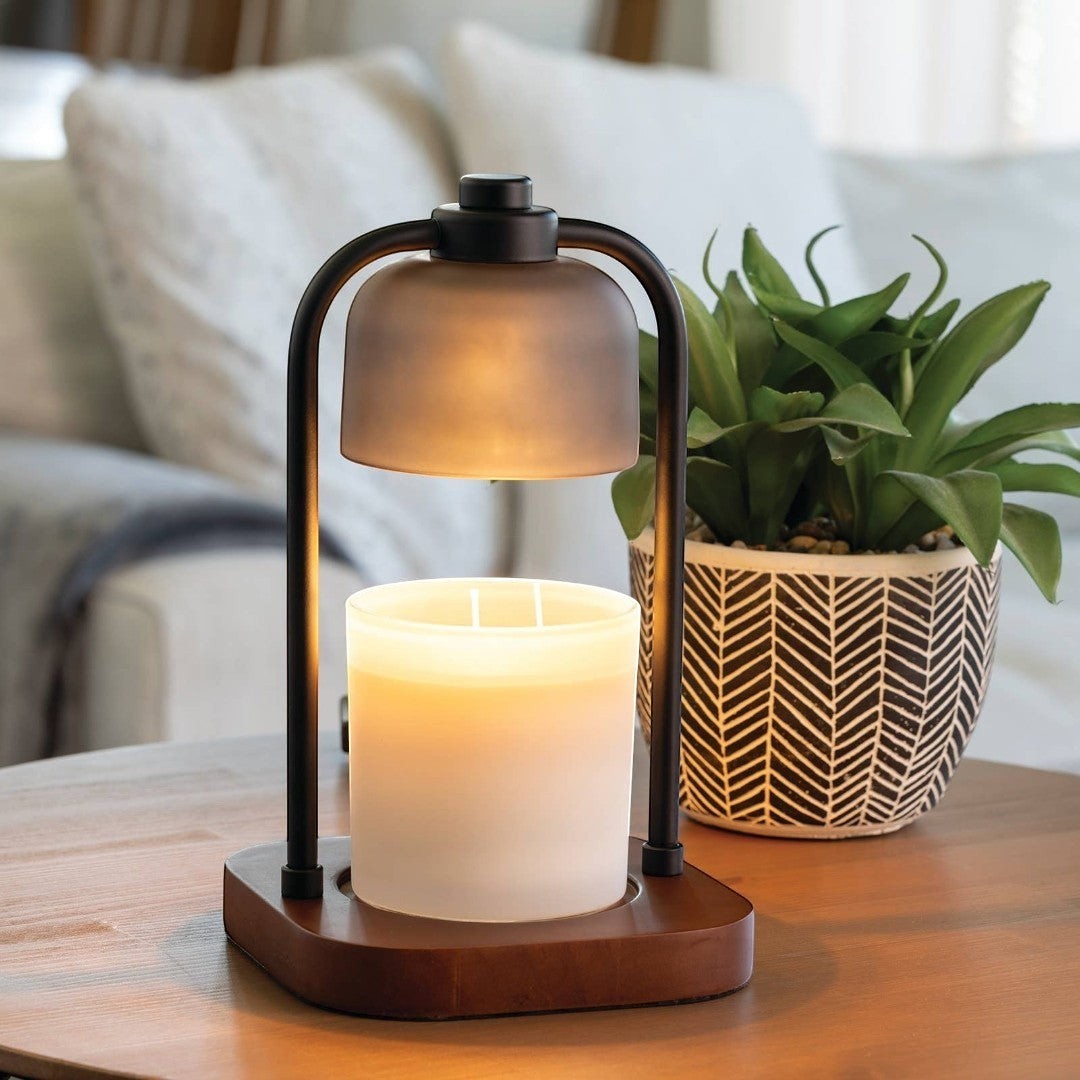 Doodlations Coffee Bar & Boutique modern candle warmer lamp with dark metal frame and wood base, gently melting a candle.