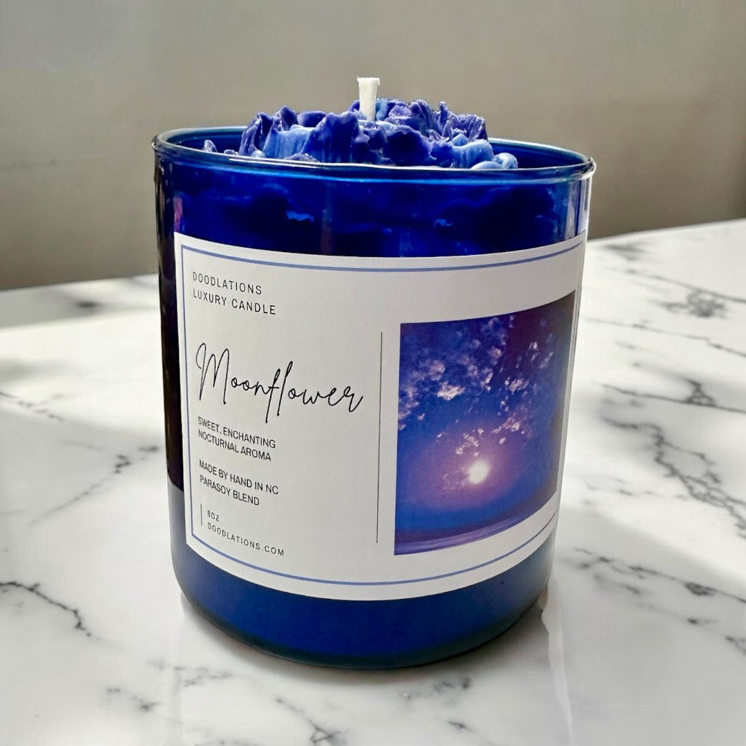 Doodlations Coffee Bar & Boutique Moonflower luxury candle in a cobalt blue jar with wax flower topper. Scented with pear, agave, florals, and musk.