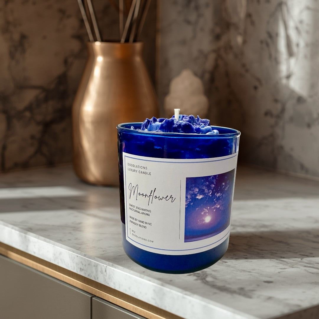 Doodlations Coffee Bar & Boutique Moonflower luxury candle in a cobalt blue jar with a wax flower topper.