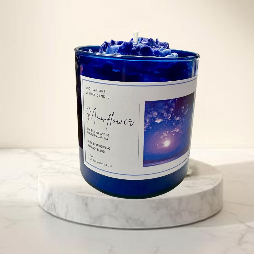 Doodlations Coffee Bar & Boutique Moonflower luxury candle in a cobalt blue jar with a wax flower topper.