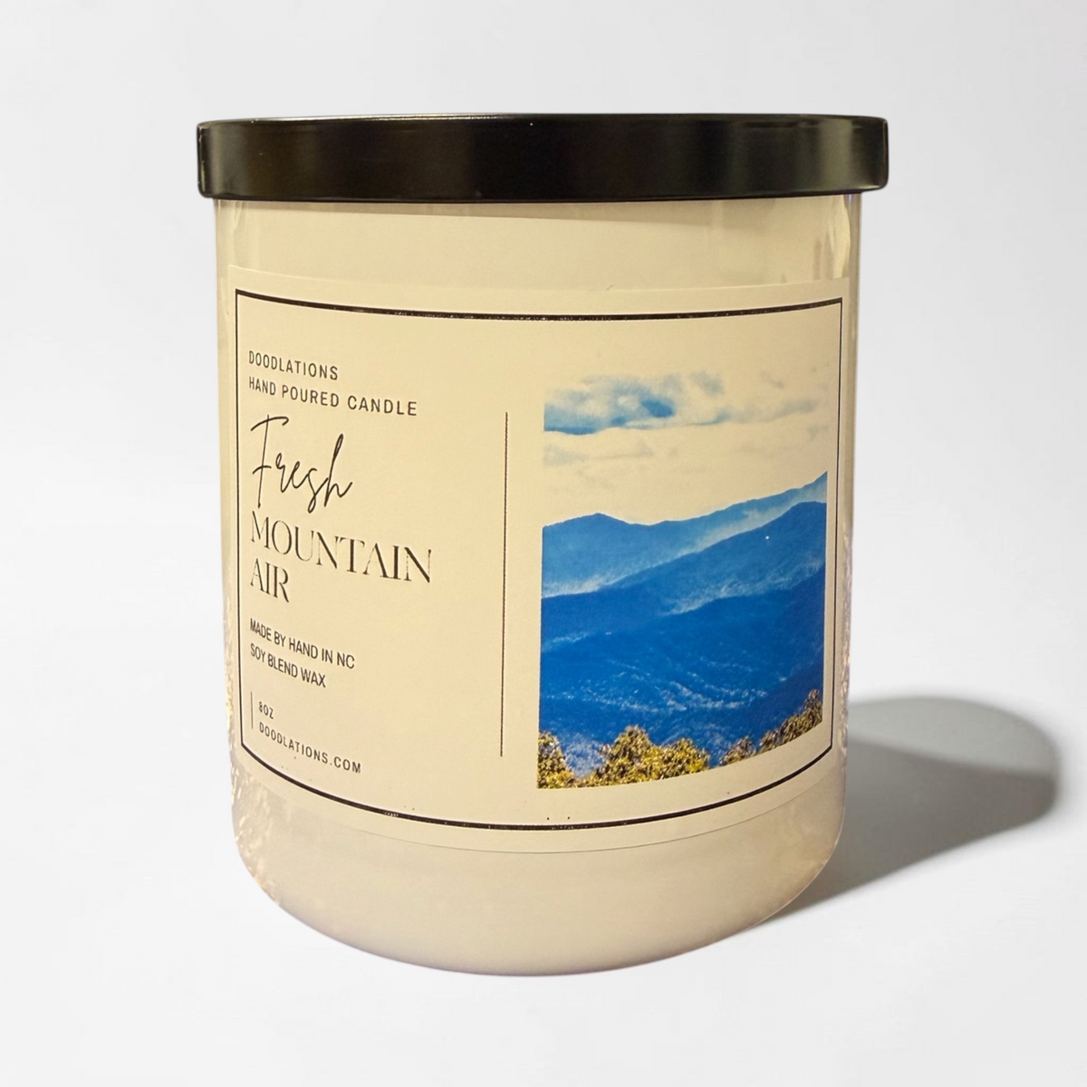 Doodlations Coffee Bar & Boutique Fresh Mountain Air luxury hand-poured soy blend candle in a glass jar with black lid.