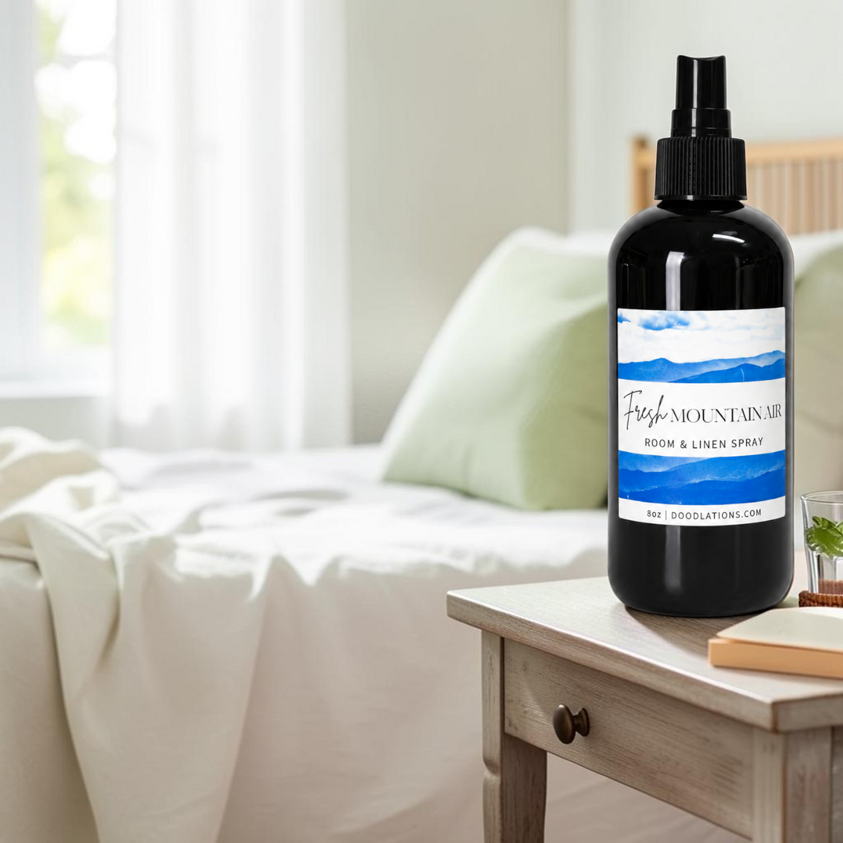 Doodlations Coffee Bar & Boutique Fresh Mountain Air room and linen spray in a black bottle on a wooden bedside table.