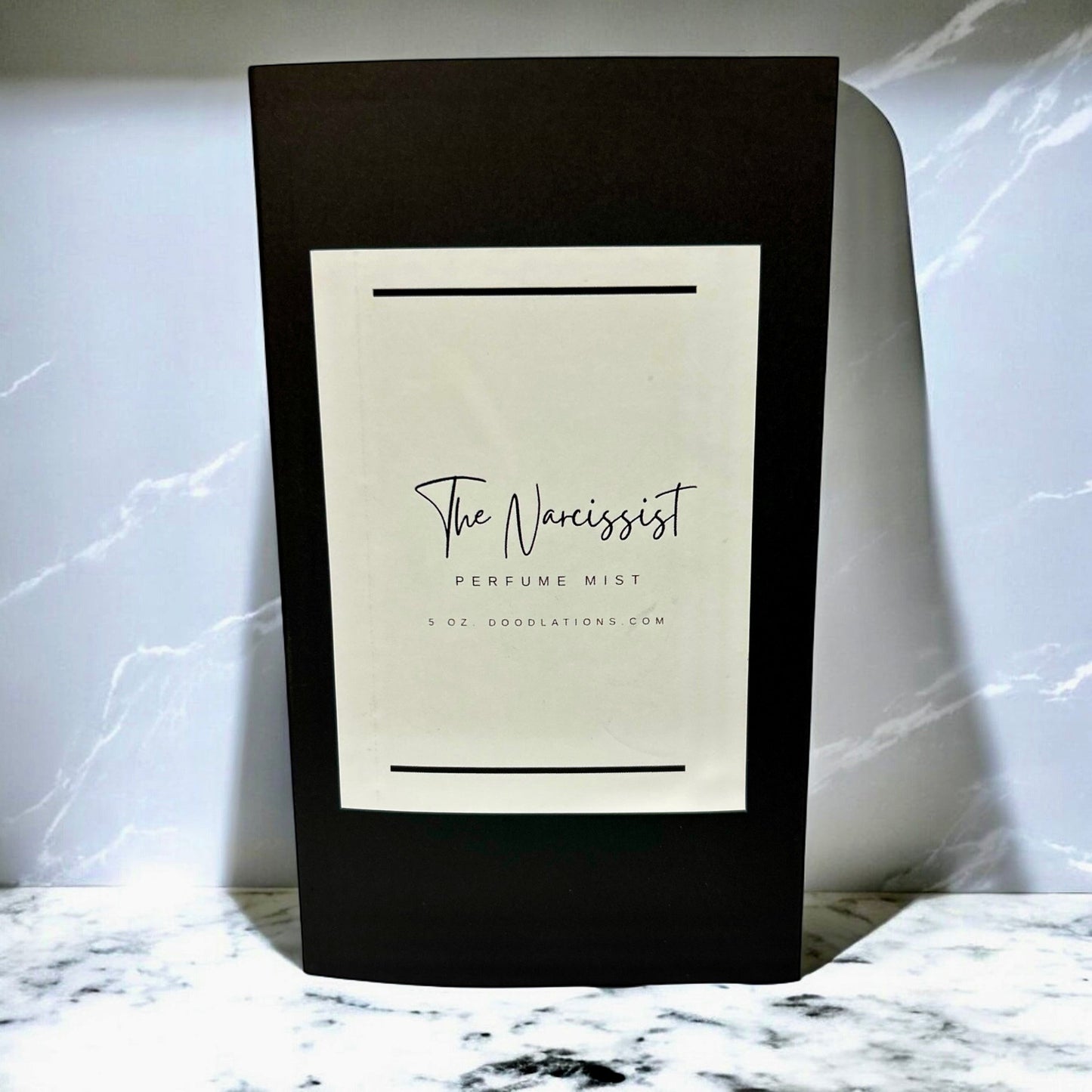 Doodlations Coffee Bar & Boutique The Narcissist luxury fine mist perfume in a sleek black bottle with white label.