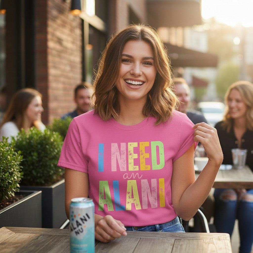 Doodlations Coffee Bar & Boutique pink 100% cotton neon graphic tee with "I NEED an ALANI" text in pastel colors.