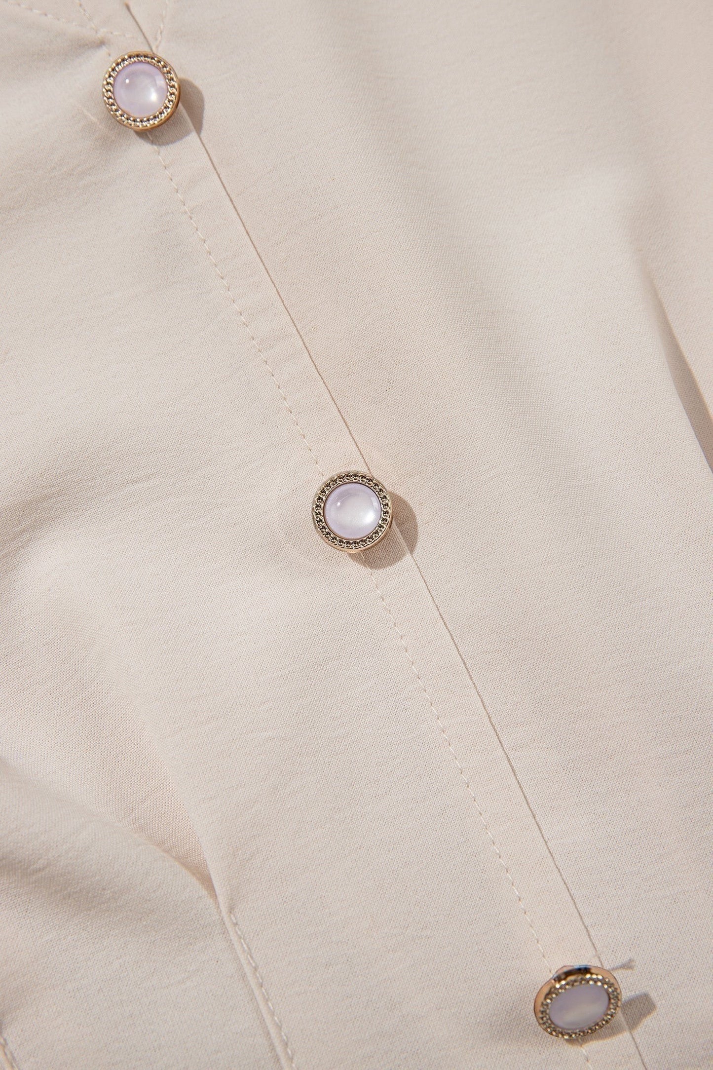 Doodlations Coffee Bar & Boutique oatmeal V-neck blouse featuring elegant pearl-like button detailing on the front.
