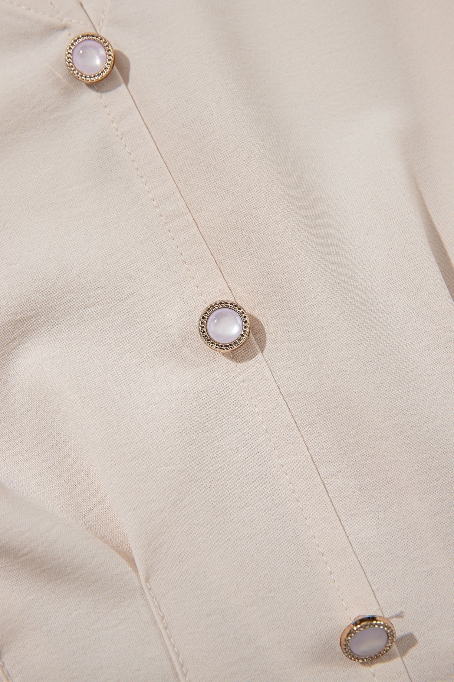 Doodlations Coffee Bar & Boutique oatmeal V-neck blouse featuring elegant pearl-like button detailing on the front.
