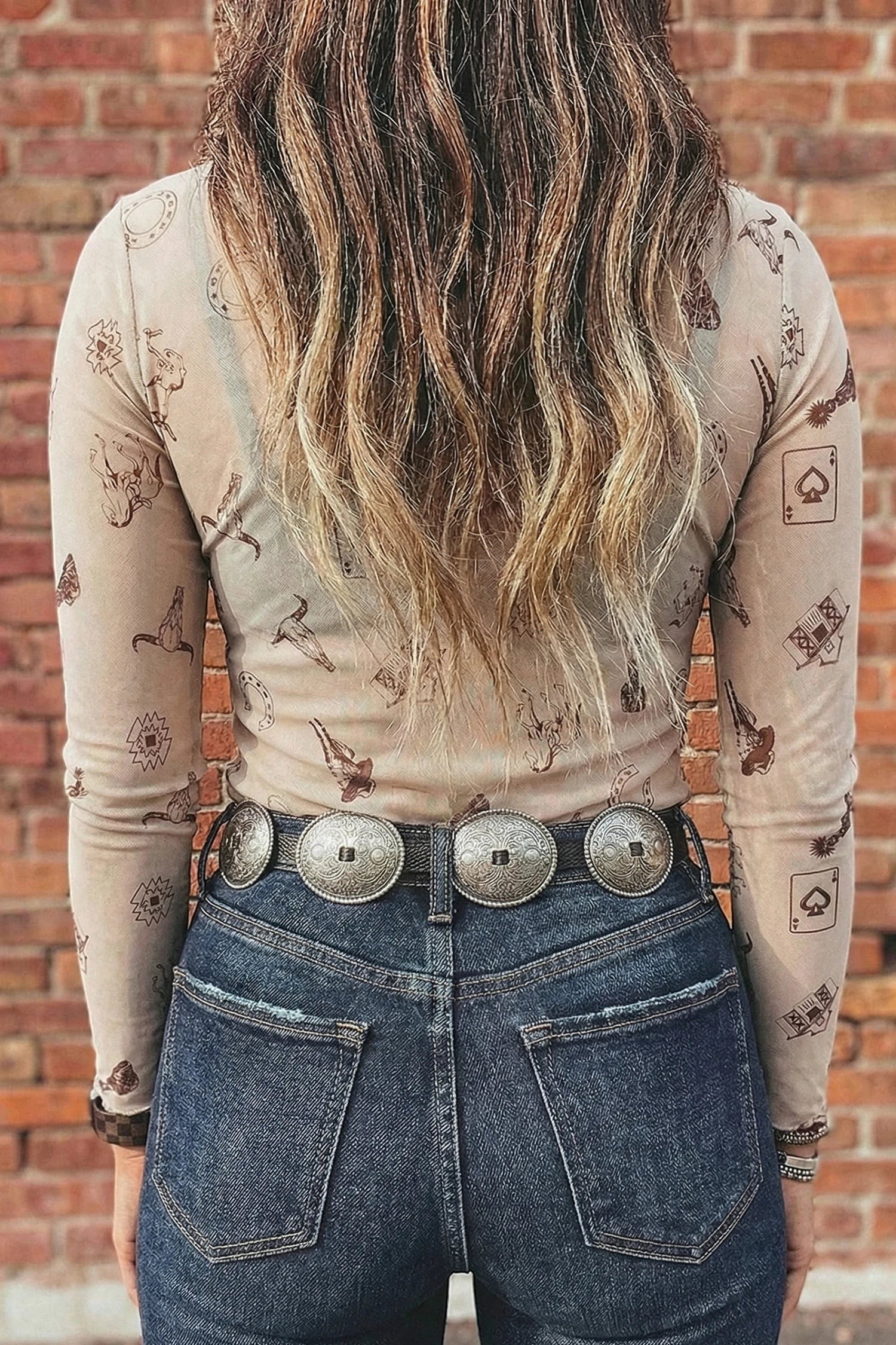Doodlations Coffee Bar & Boutique oatmeal mesh long sleeve top with Western print, mock neck, and silver concho belt.