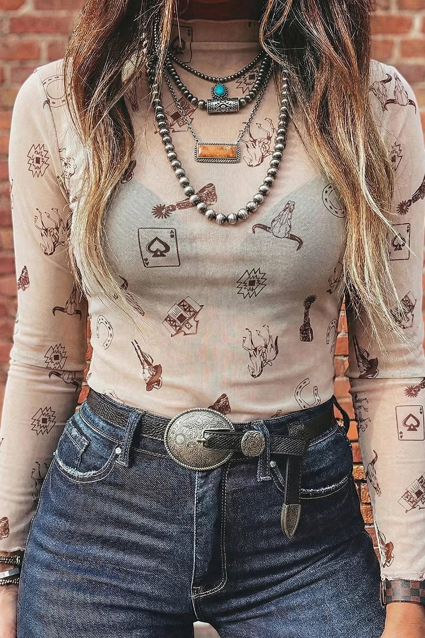 Doodlations Coffee Bar & Boutique oatmeal mesh long sleeve mock neck top with Western print, worn with dark denim.