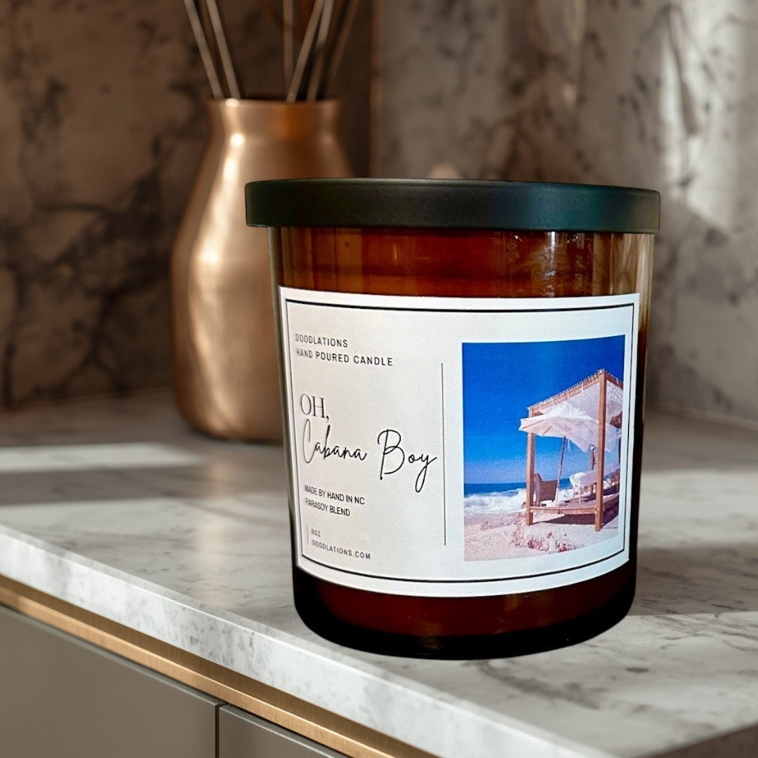 Doodlations Coffee Bar & Boutique Oh Cabana Boy luxury hand-poured candle with tropical beach scene label.