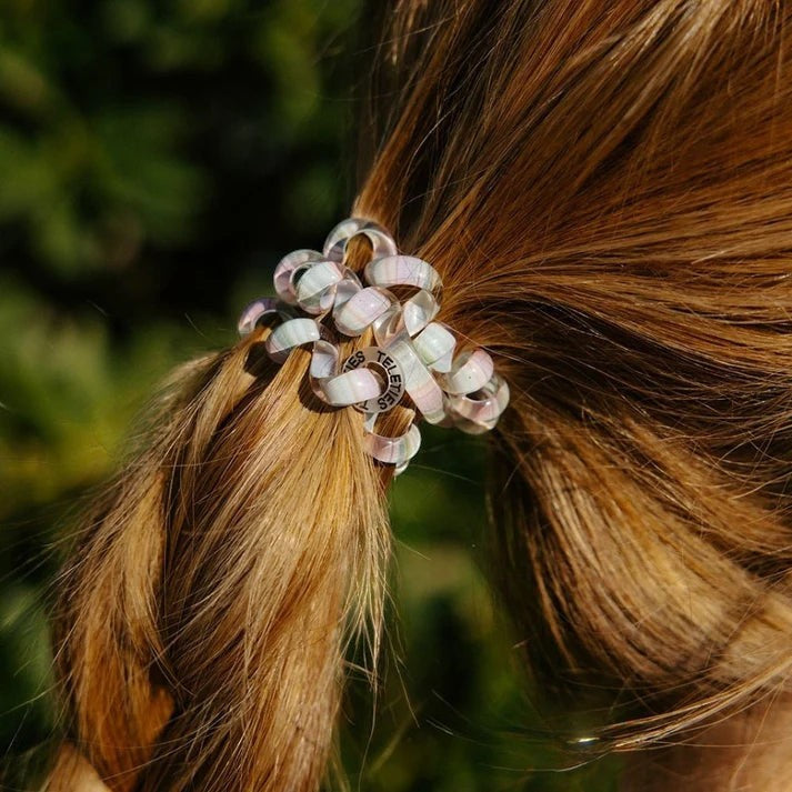 Doodlations Coffee Bar & Boutique Opal Glow hair ties in purple and green shimmer worn in a ponytail.