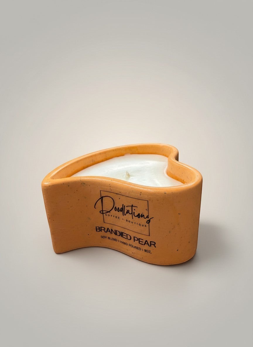 Doodlations Coffee Bar & Boutique orange concrete heart-shaped candle with Brandied Pear scent.