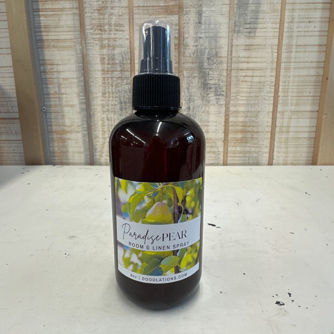 Doodlations Coffee Bar & Boutique Paradise Pear room and linen spray in a dark amber bottle with a spray nozzle.