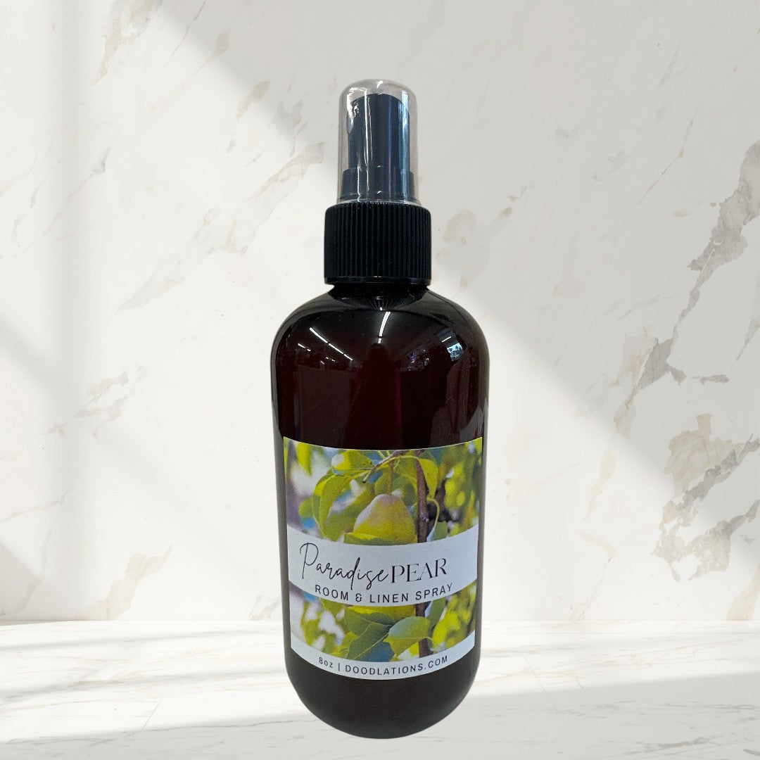 Doodlations Coffee Bar & Boutique Paradise Pear room and linen spray in a dark amber bottle with a spray nozzle.