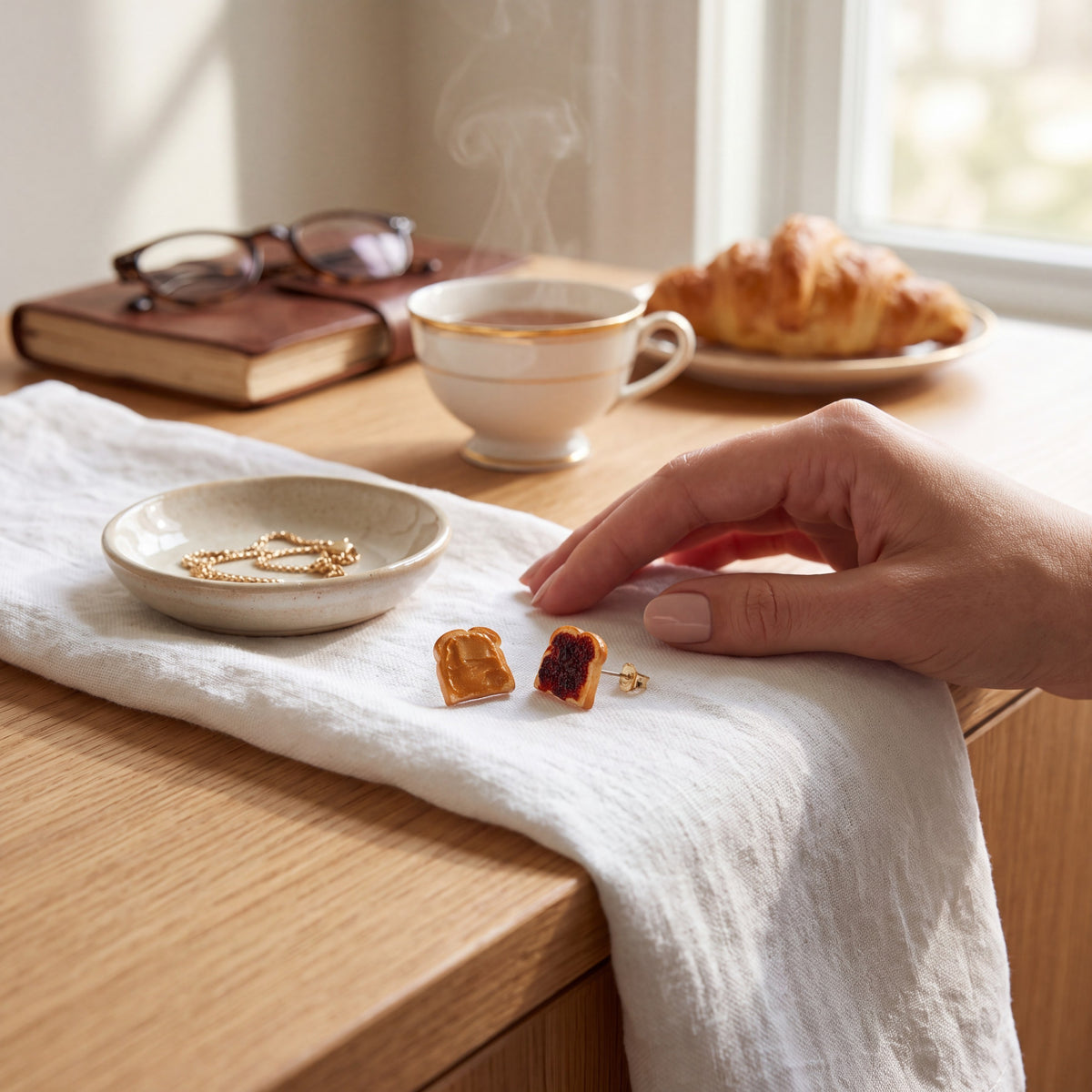 Doodlations Coffee Bar & Boutique handmade peanut butter and jelly toast stud earrings on a white linen cloth.