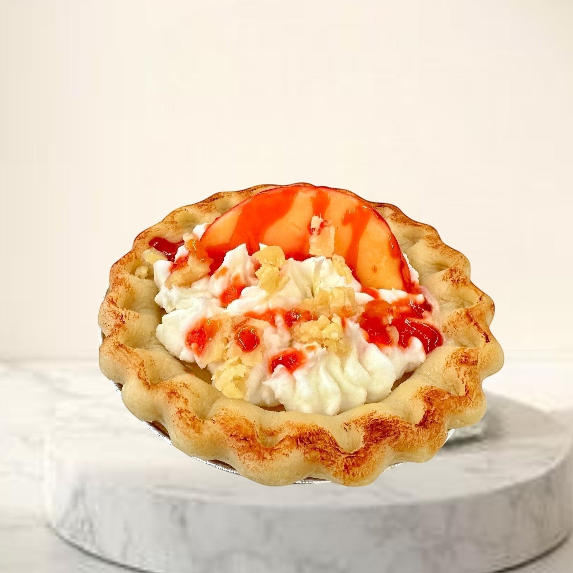Doodlations Coffee Bar & Boutique Peach Pie candle designed to look like a real pie with whipped cream and fruit topping.