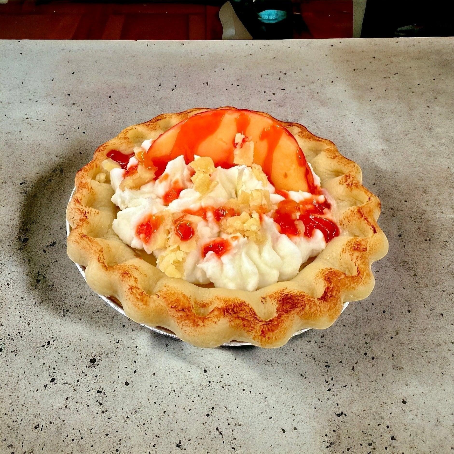 Doodlations Coffee Bar & Boutique Peach Pie candle designed to look like a real pie with whipped cream, peach slices, and strawberry drizzle.