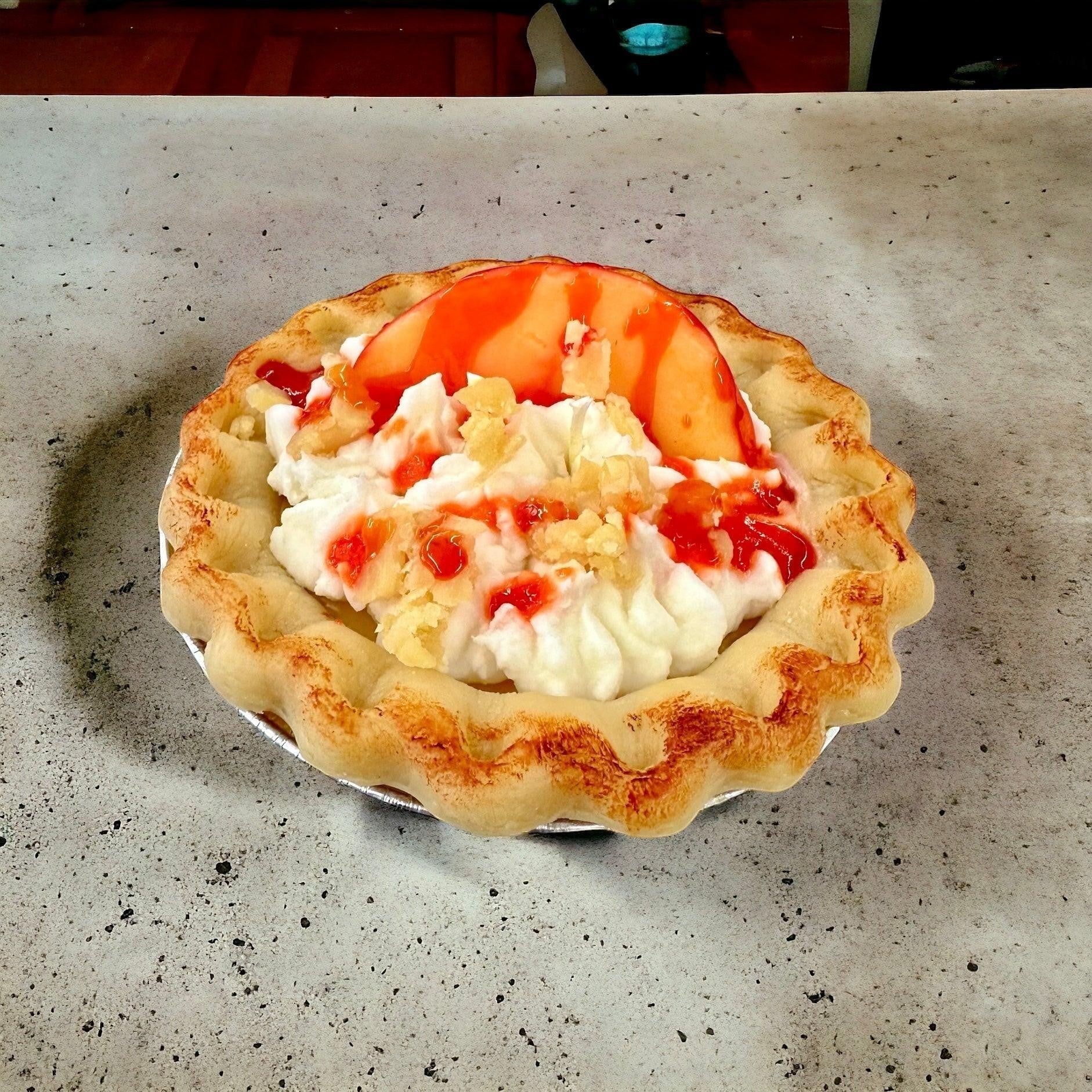 Doodlations Coffee Bar & Boutique Peach Pie candle designed to look like a real pie with whipped cream, peach slices, and strawberry drizzle.