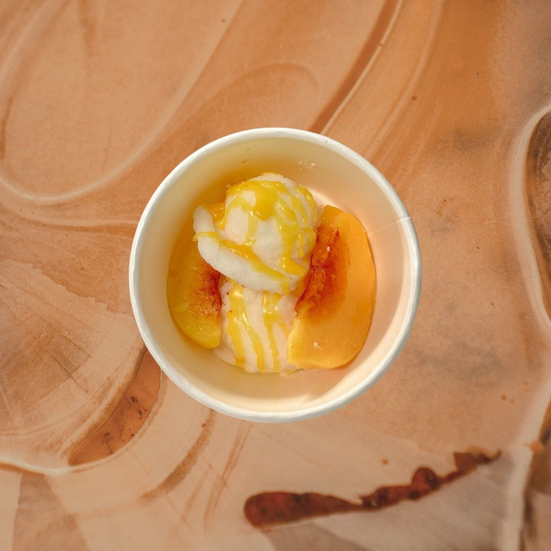 Doodlations Coffee Bar & Boutique Peaches and Cream wax melts shaped like ice cream with peach slices and yellow drizzle.