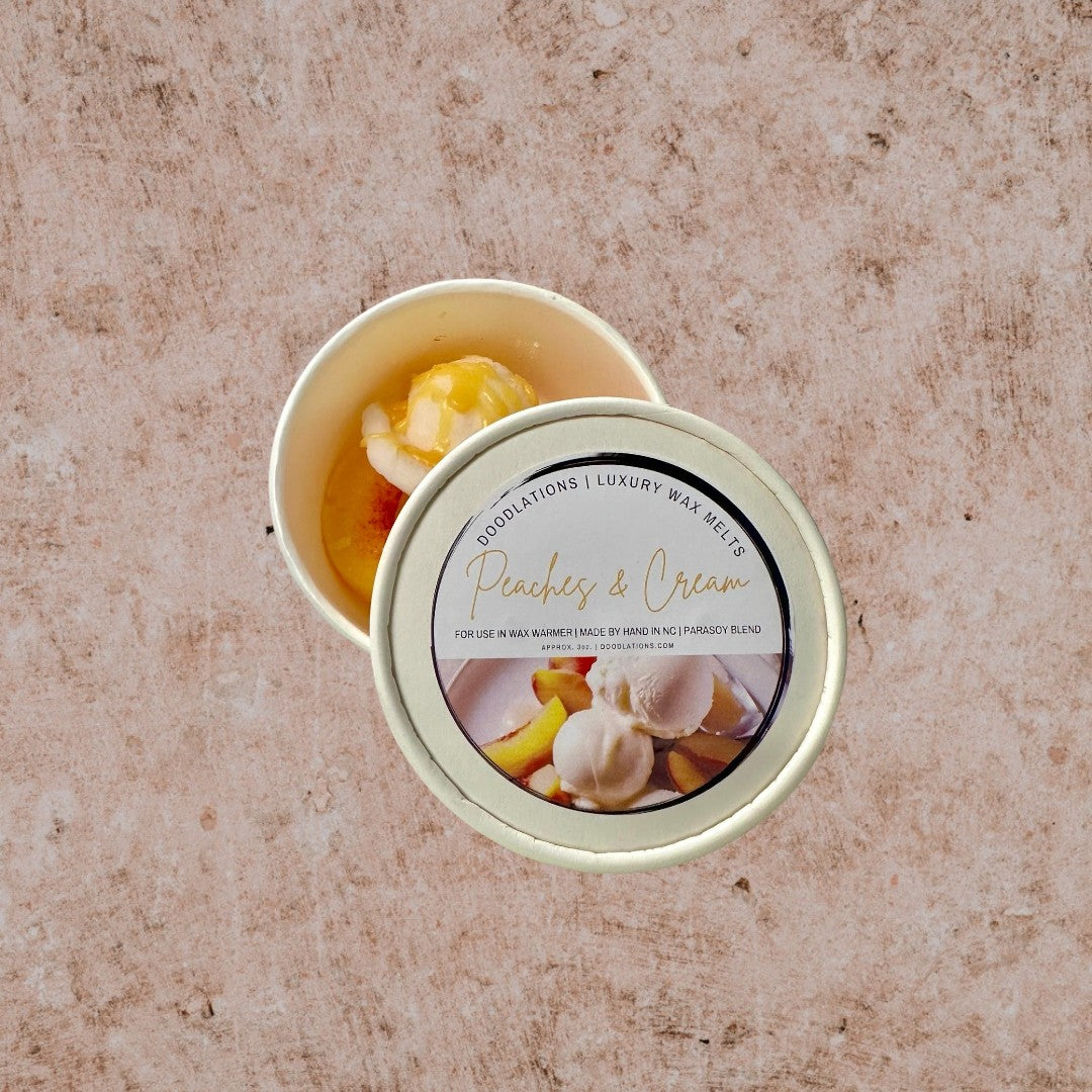 Doodlations Coffee Bar & Boutique Peaches & Cream wax melts in a white container, resembling scoops of ice cream with peach slices.