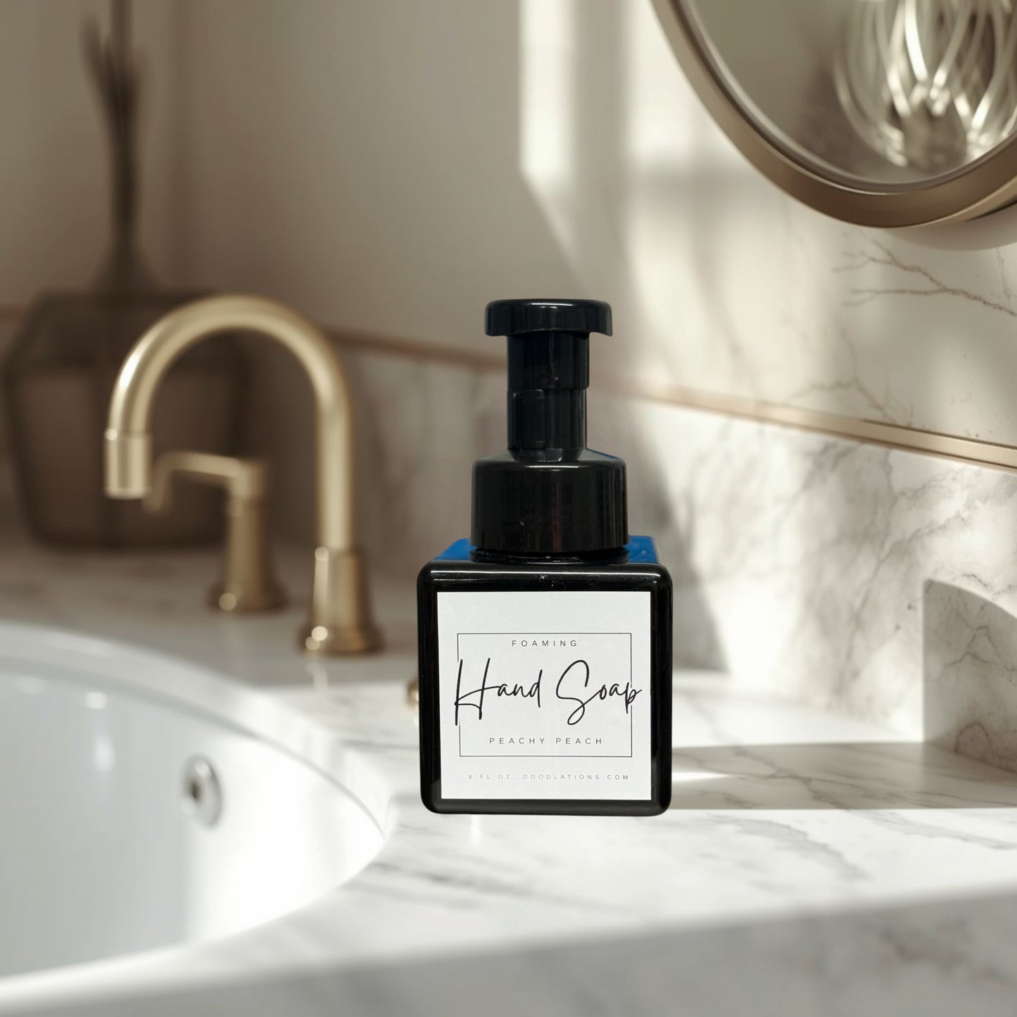 Doodlations Peachy Peach foaming hand soap in a black square bottle with a black pump dispenser. Surrounded by green artificial plants.