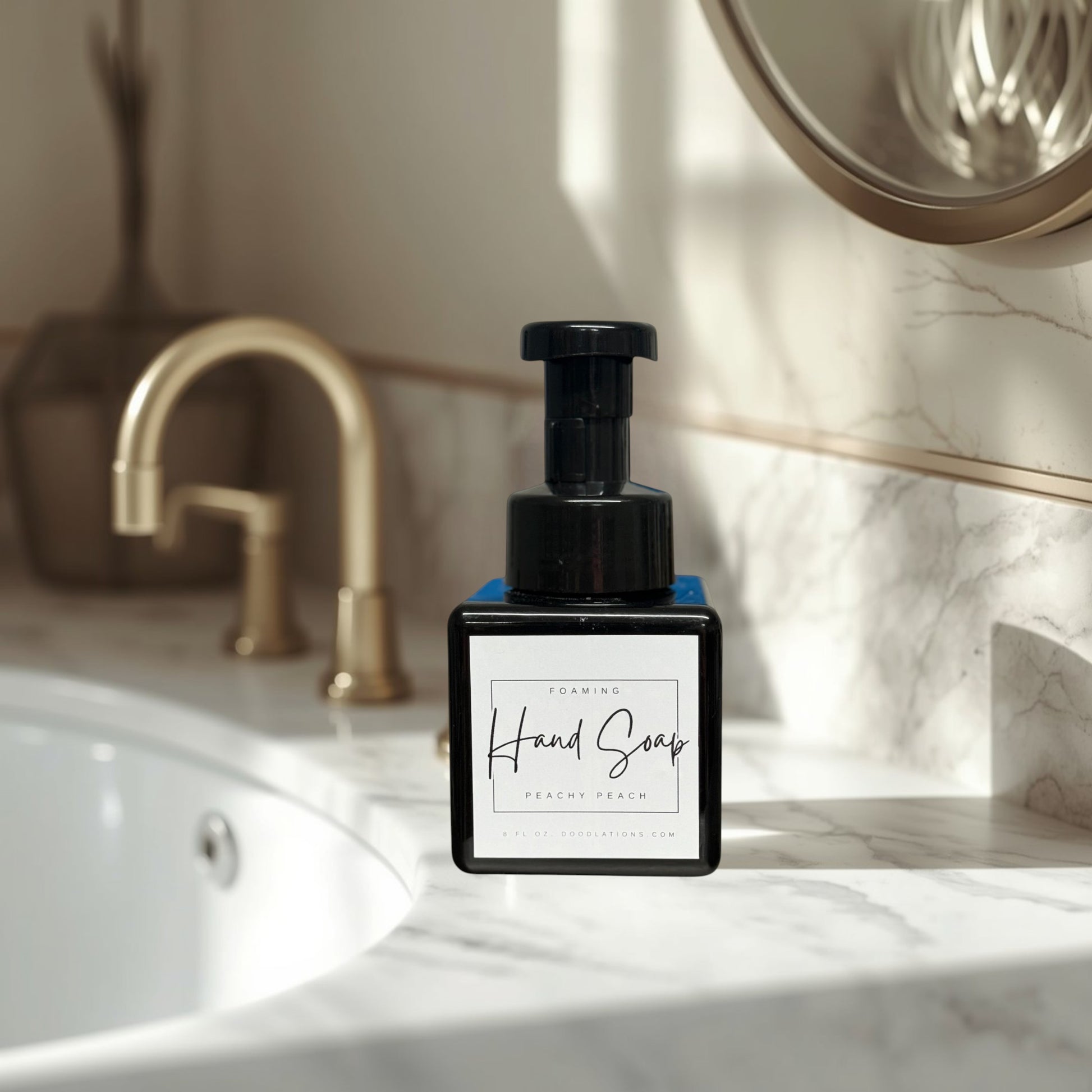 Doodlations Peachy Peach foaming hand soap in a black square bottle with a black pump dispenser. Surrounded by green artificial plants.