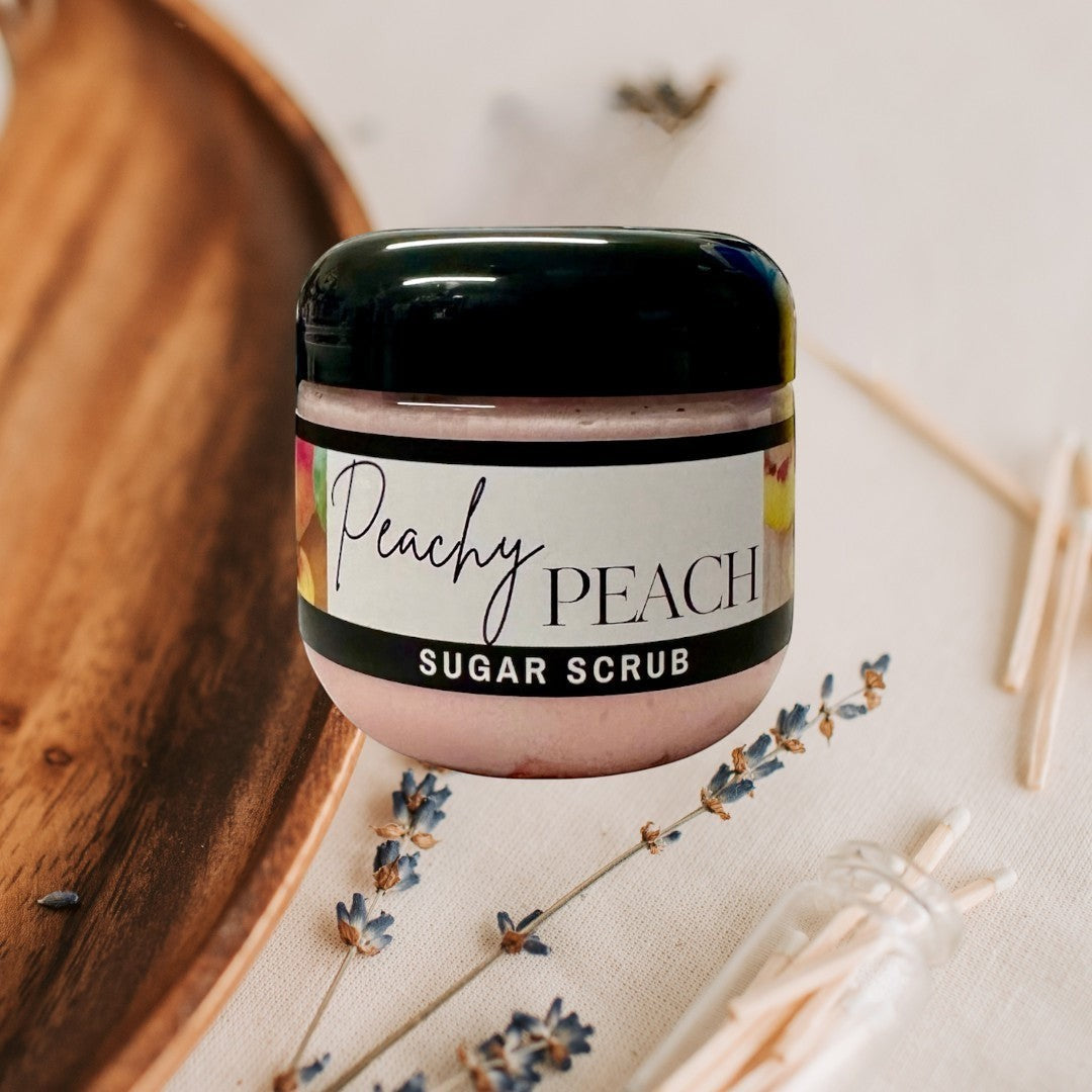 Doodlations Coffee Bar & Boutique Peachy Peach sugar scrub in a clear jar with a black lid. Pink scrub with peach imagery.