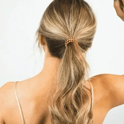 Doodlations Coffee Bar & Boutique Peppermint hair tie in a copper spiral design worn in a ponytail on blonde hair