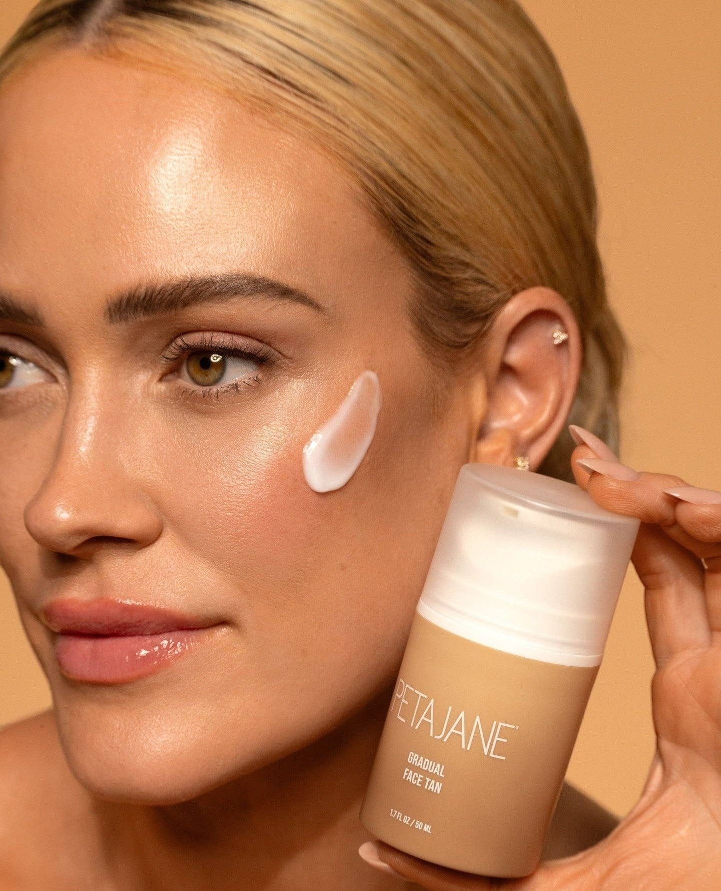 Doodlations Coffee Bar & Boutique Petajane Gradual Face Tan cream applied to a model's cheek for a sun-kissed glow.