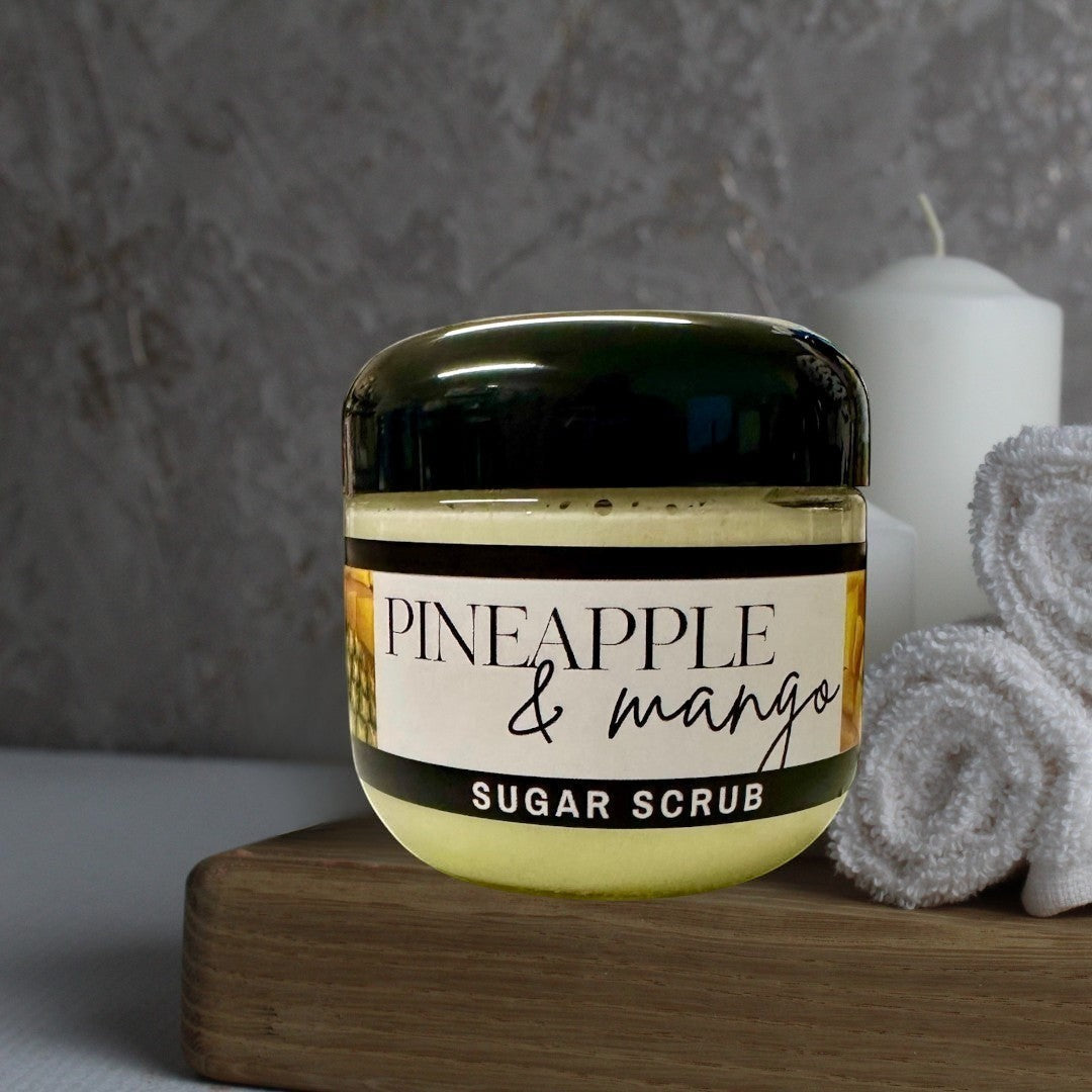 Doodlations Coffee Bar & Boutique Pineapple Mango sugar scrub in a clear jar with a black lid, light yellow scrub inside.