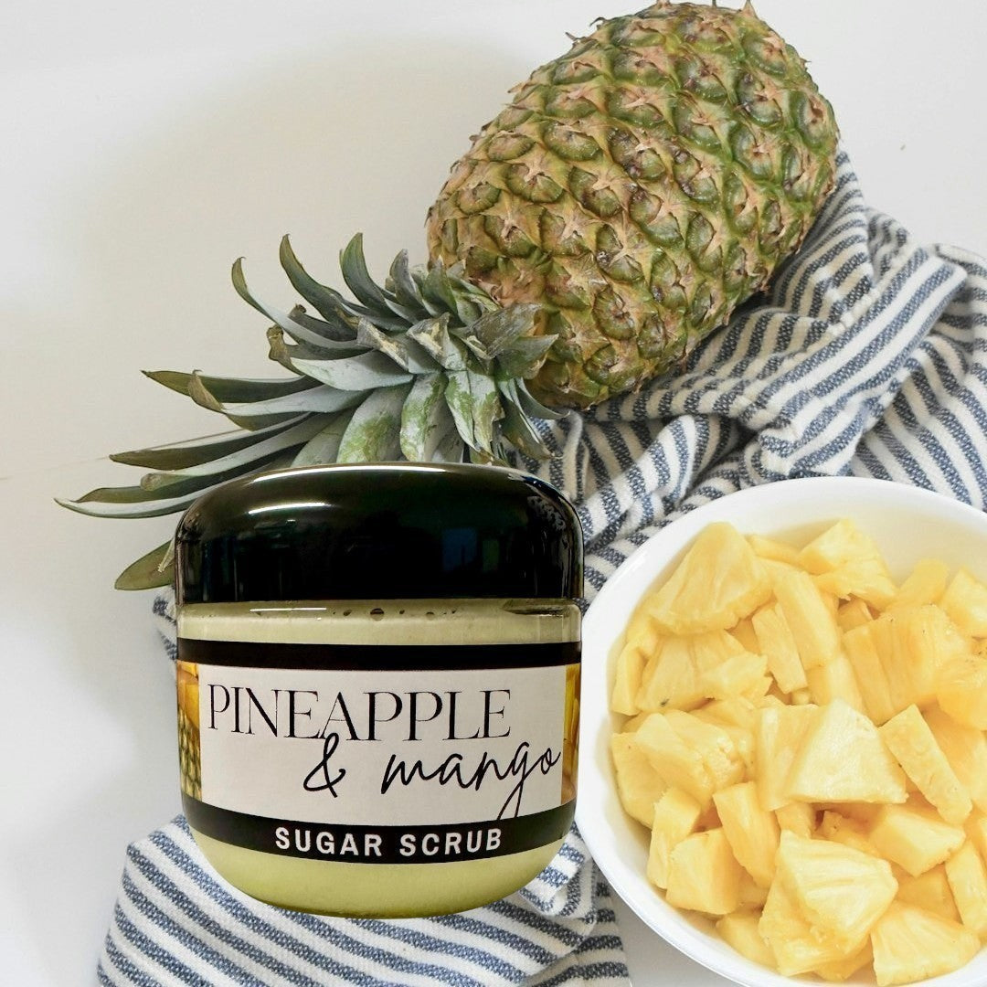 Doodlations Coffee Bar & Boutique Pineapple Mango sugar scrub in a clear jar with a black lid, light yellow scrub inside.
