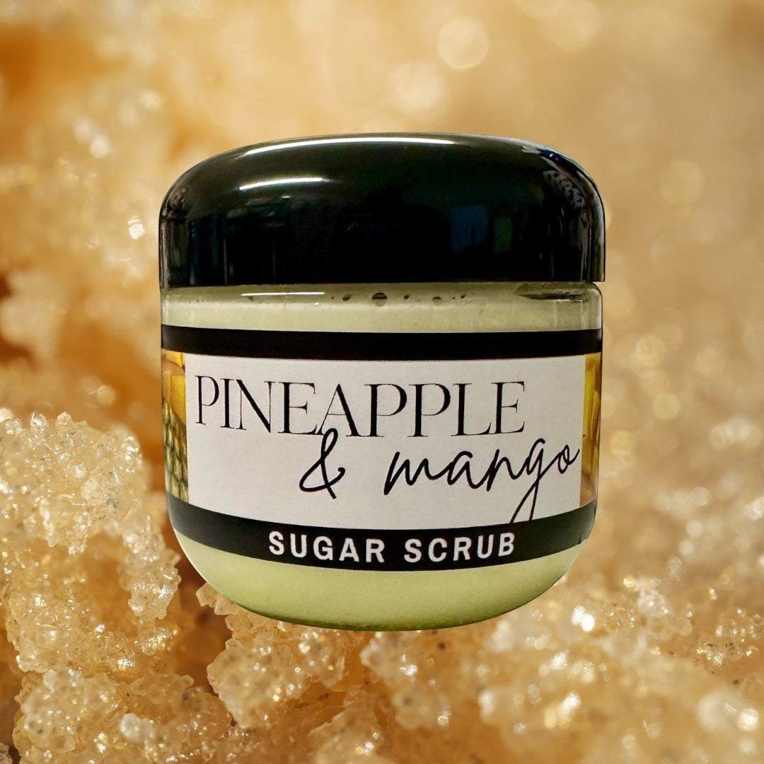 Doodlations Coffee Bar & Boutique Pineapple Mango sugar scrub in a clear jar with a black lid. Light yellow scrub with pineapple and mango graphics.