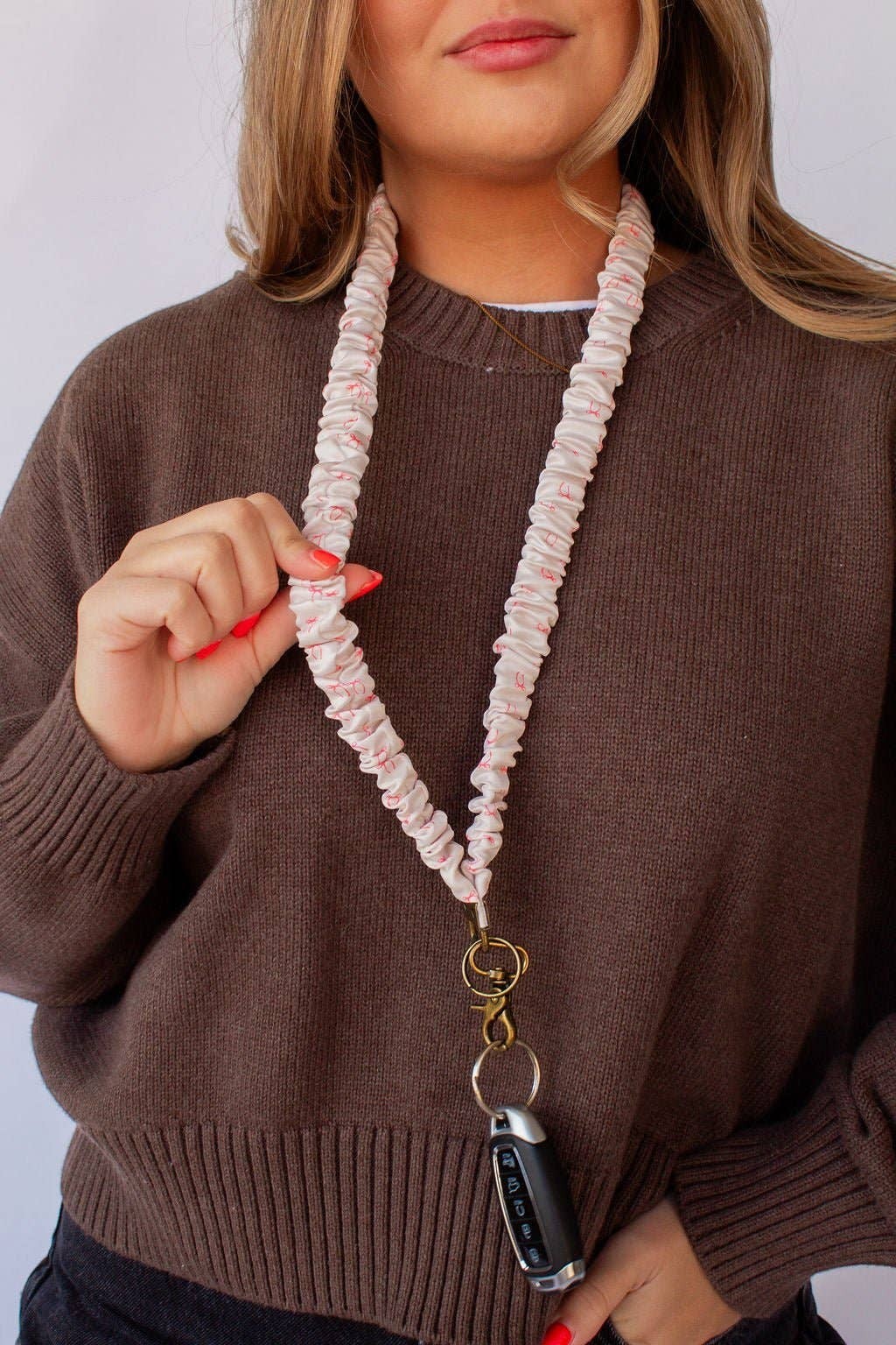 Doodlations Coffee Bar & Boutique pink bow print textured polyester lanyard worn around a woman's neck