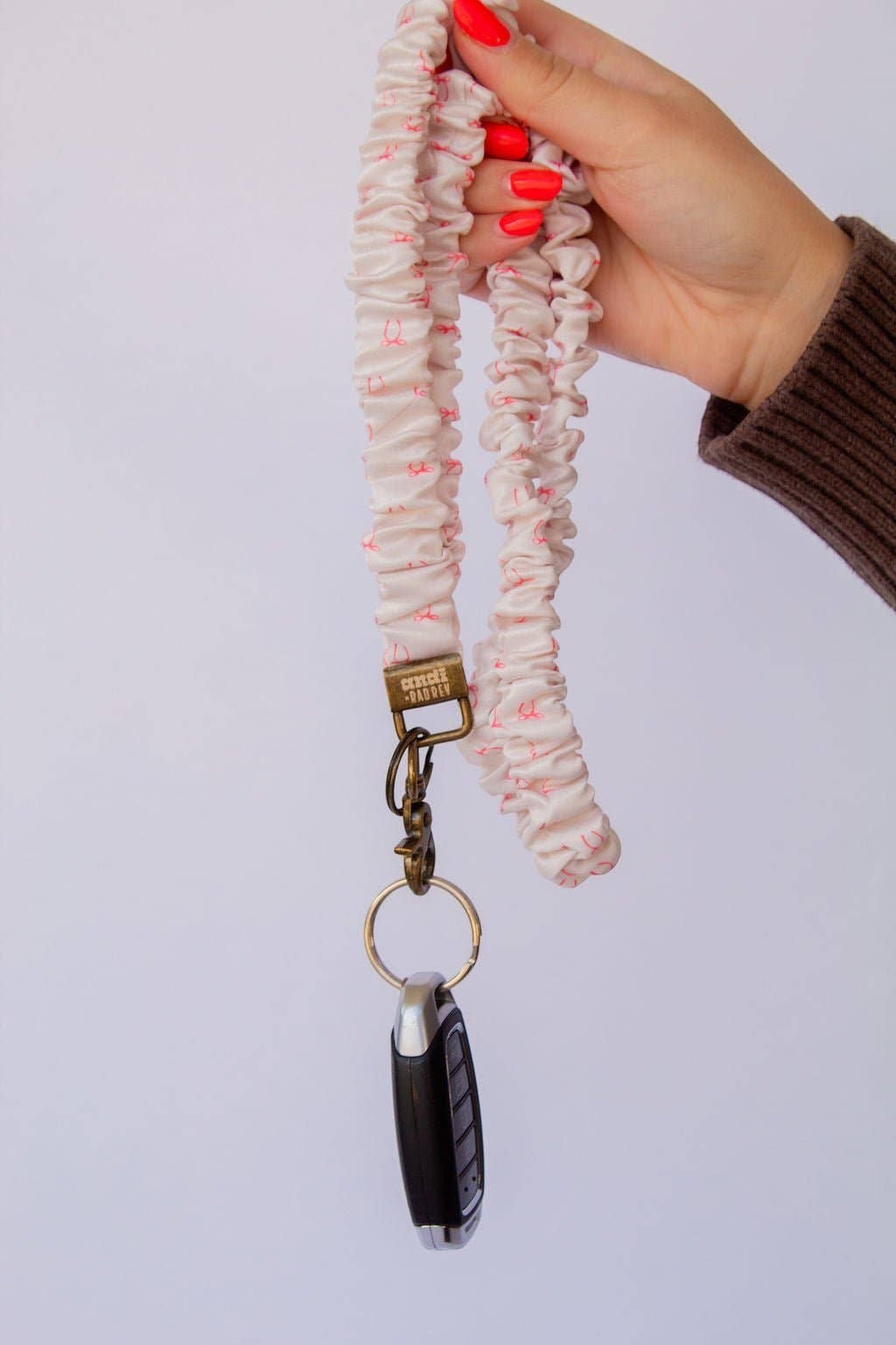 Doodlations Coffee Bar & Boutique pink bow print scrunchie lanyard with a key fob held in a hand