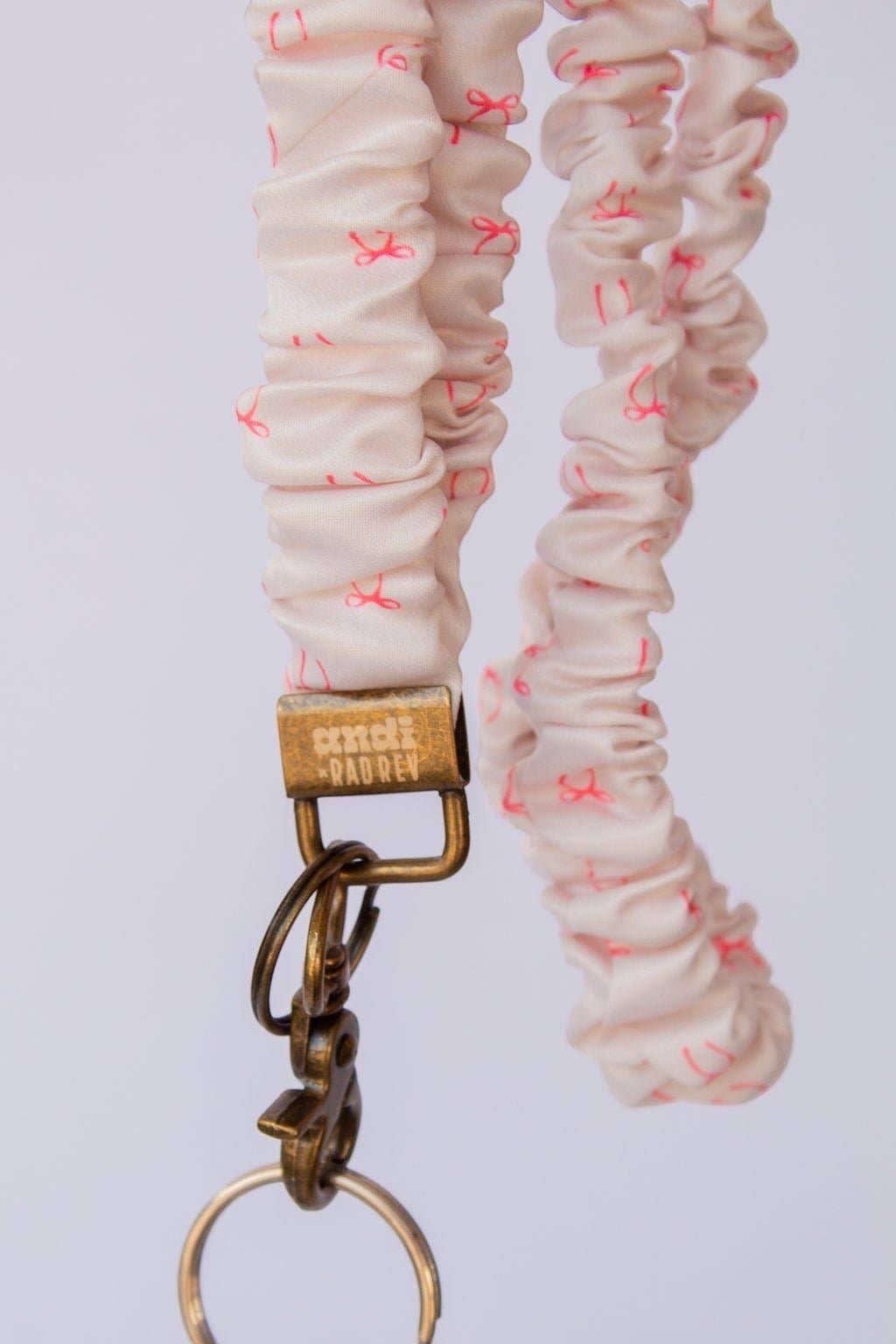 Doodlations Coffee Bar & Boutique pink bow print textured polyester scrunchie lanyard with antique brass hardware