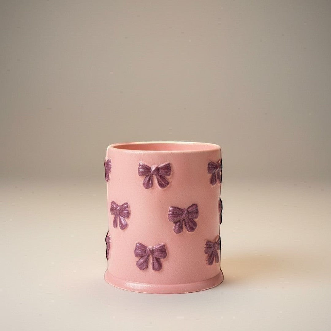 Doodlations Coffee Bar & Boutique pink concrete candle with purple bow accents and soy blend wax. 8oz.