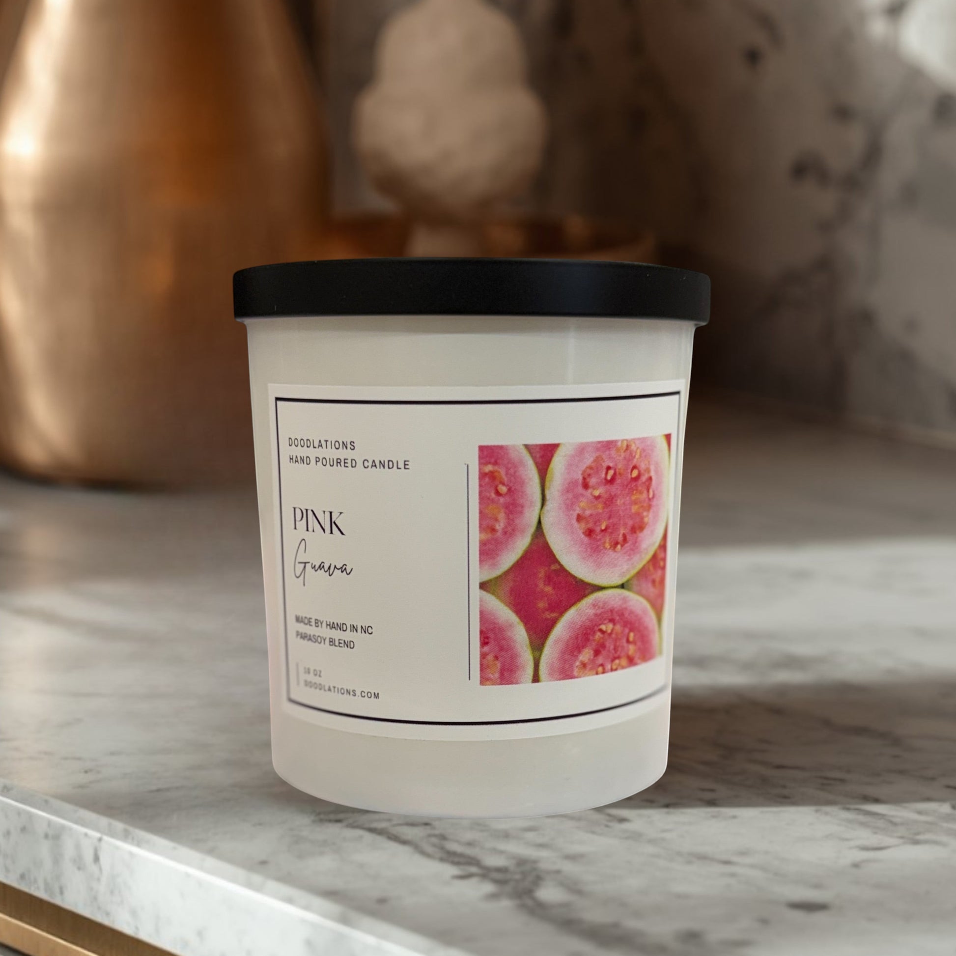 Doodlations Coffee Bar & Boutique Pink Guava hand-poured parasoy blend candle with a tropical beach background.
